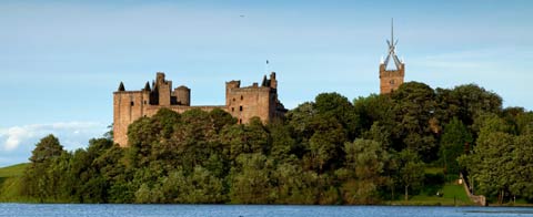 The modern steeple of St Michael's church and the ruins of Linlithgow Palace seen from the banks of the pretty loch