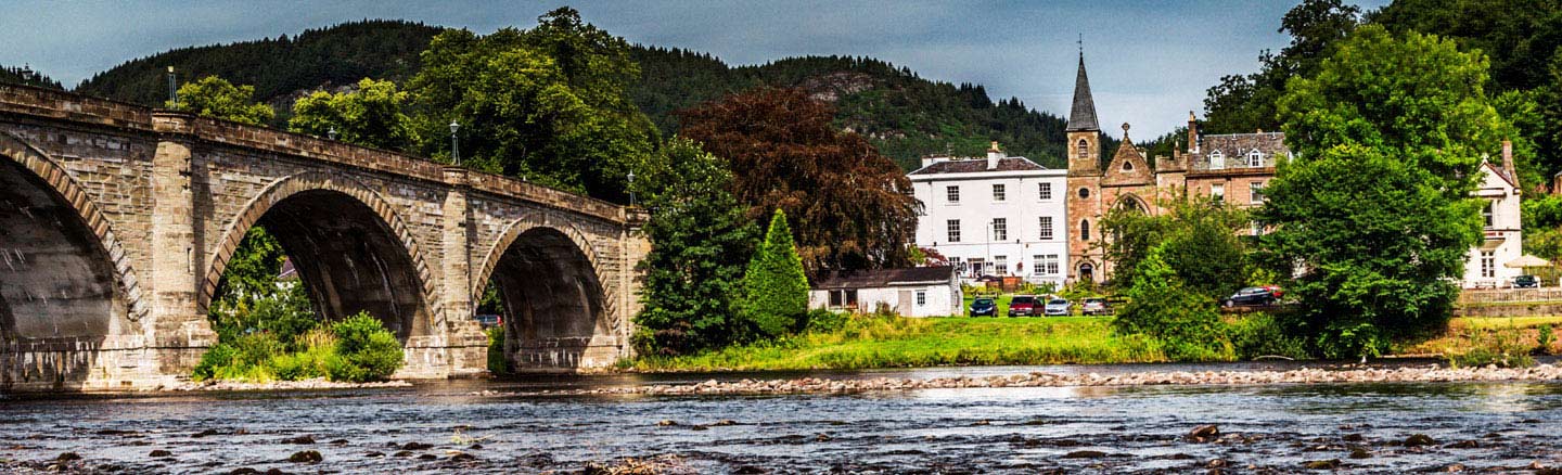 White painted buildings of Dunkeld seen across the tumbling waters of the River Tay