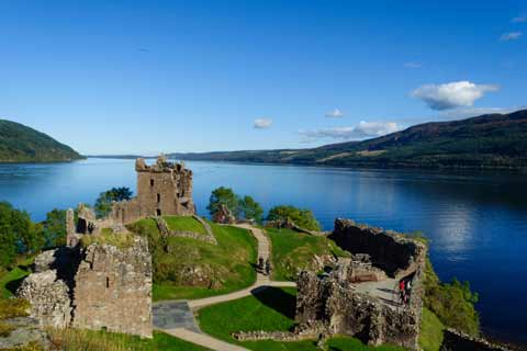 Summer view of the ruins of Urquart Castle overlooking the blue waters of Loch Ness
