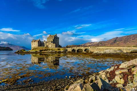 Eilean Donan Castle and the bridge to its little island seen from the banks of Loch Duich at low tide