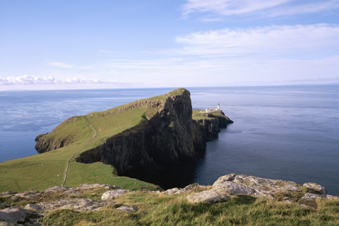 Looking along the rugged coastline of Neist Point, Isle Of Skye, towards the white-washed lighthouse overlooking The Minch