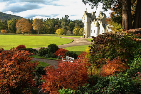 Autumn leaves contrast with the green lawn and blonde stonework of Ballindalloch Castle