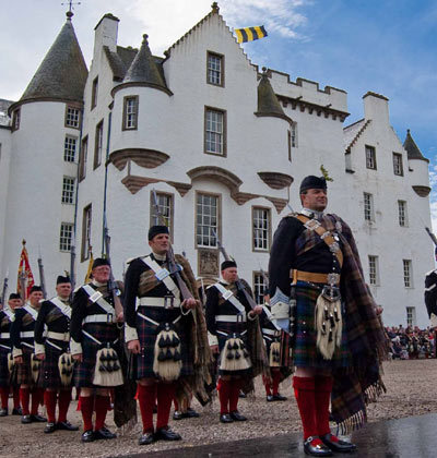 Atholl Highlanders standing to attention outside white-washed Blair Castle