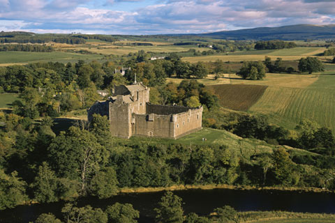 Medieval Doune castle sitting at an elevated position surrounded by woods at a bend of the River Teith