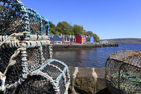 Colourful buildings overlook Tobermory Bay with lobster creels in the foreground