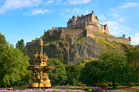 Edinburgh Castle atop rock viewed from Princes Street gardens with fountain in foreground