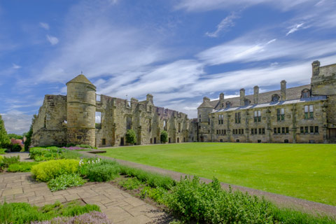 Falkland Palace - grey stone palace set amongst lawns and tidy gardens on a bright day
