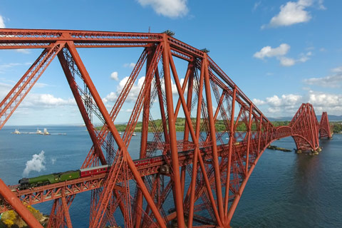 steam train on the Red iron Forth Rail Bridge crossing the River Forth on a bright day