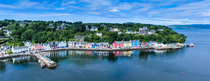 Tobermory - colourul houses along the bay and blue sky reflected in calm water 