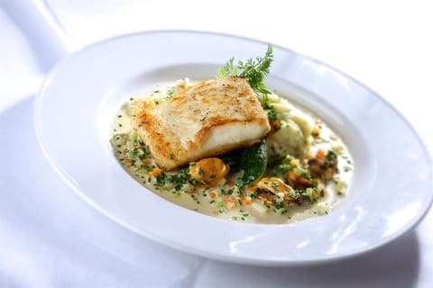 An appetising plate of baked cod served with mussels and mash in a creamy sauce