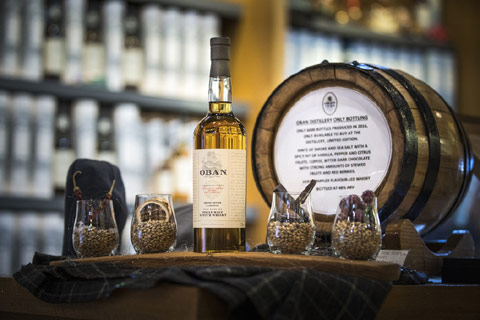 A bottle of Oban Whisky with sample glasses of barley on a tartan draped tray