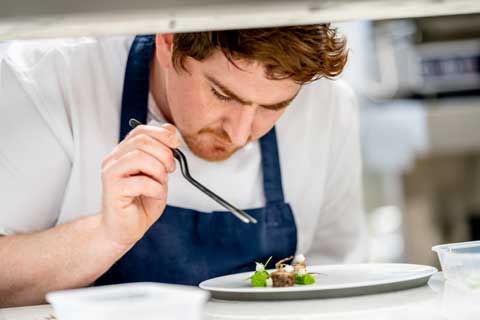 A chef preparing a fine dining plate