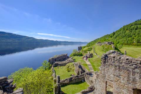 Summer view of the ruins of Urquhart Castle overlooking the calm waters of Loch Ness