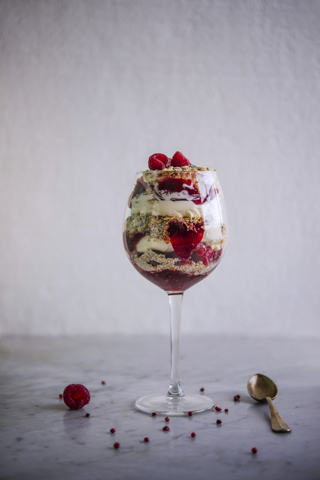 A wine glass filled with Cranachan and decorated with raspberries