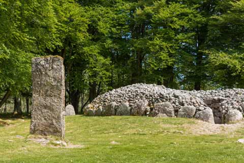Standing stone and passage grave seen amongst the trees at Clava Cairns