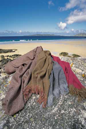 Colourful Harris Tweed draped on a rock by a beach