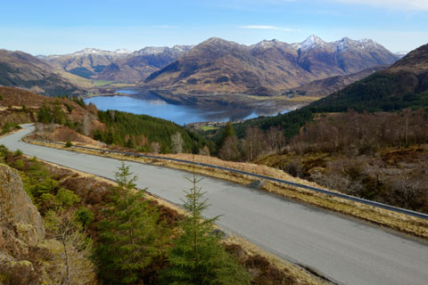 Winding road descends to the banks of Loch Duich with the mountains of Kintail in the background
