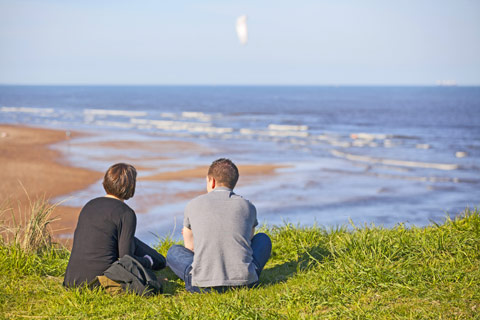 man and woman sitting on grass overlooking Aberdeen Beach
