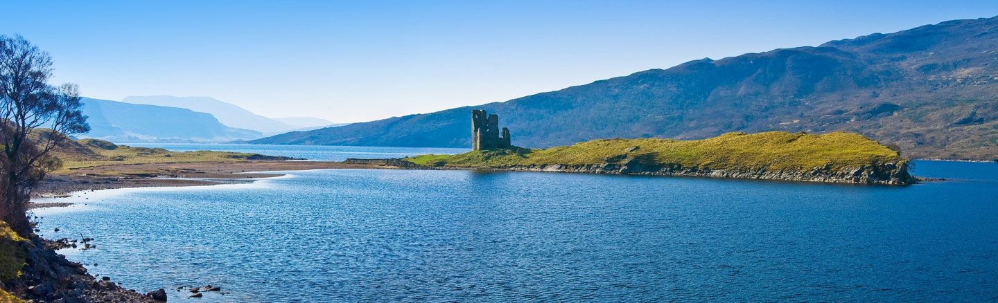 The ruins of Ardvreck Castle sitting on a grass-covered island looking over Loch Assynt 