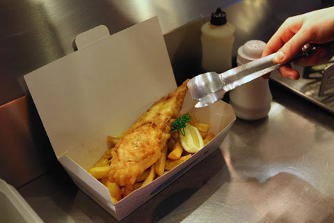 server placing fish and chips into a take away box
