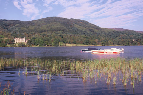 Two speedboats at anchor on Loch Achray with a turreted building on the opposite shore