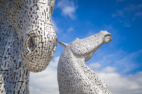 The stainless steel Kelpies horse head statues seen against a blue sky