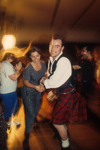 Man in kilt and woman in jeans and top dancing at a Ceilidh