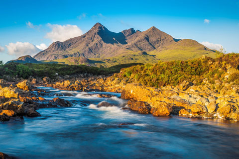 blue water foaming at rocky inlet with Cuillin Hills in the background