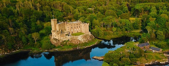 Dunvegan Castle - sand coloured stone castle set on small loch and surroubded with lush forest
