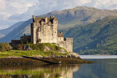 Eilean Donan Castle situated on loch with dramatic mountains in the background