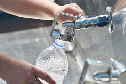 Two hands seen filling a water bottle from a tap